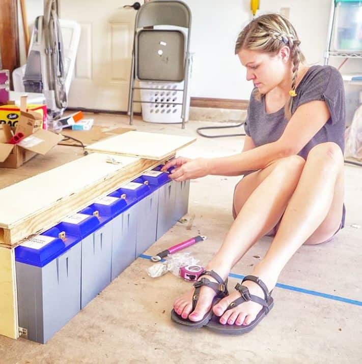 Stephanie is sitting on the ground in front of 6 Battle Born Batteries.