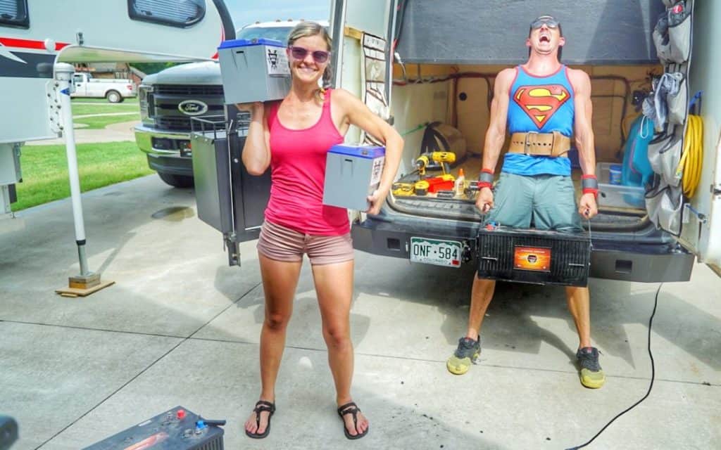 A woman holding Battle Born Batteries next to a man struggling to hold an AGM battery