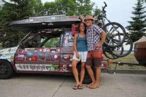 The YogaSlackers smile and stand in front of their car which is covered in stickers.