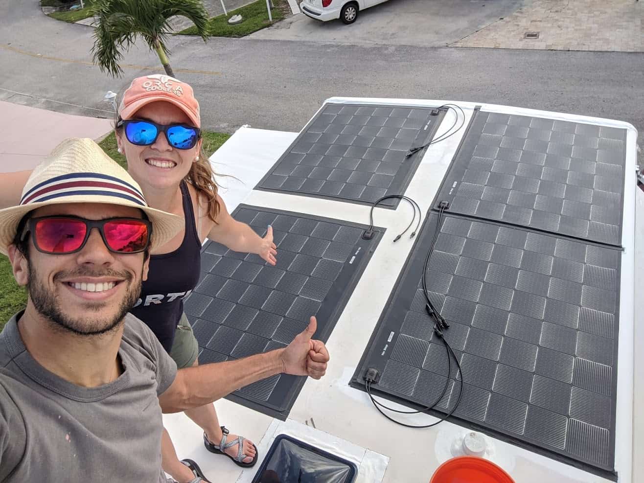 Tom and Cait Morton on the roof of their RV giving their solar panels the thumbs up