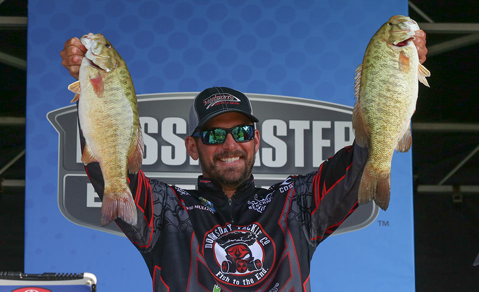 David Mullins holding up two bass that he caught at the Bassmaster