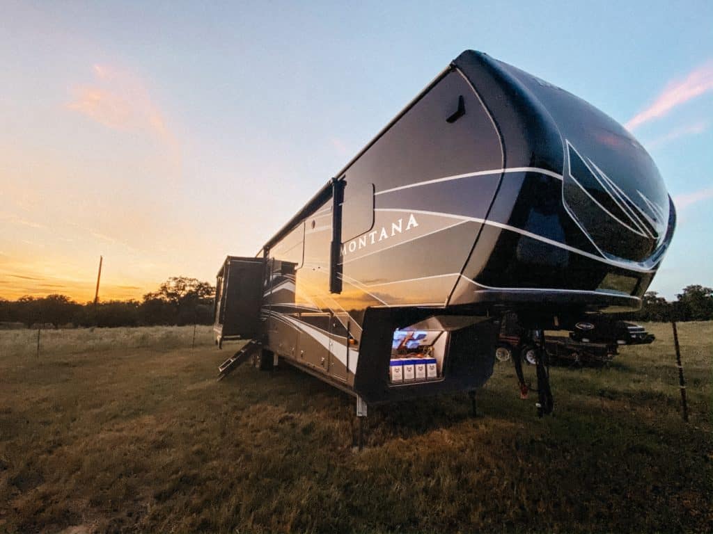 A 2020 Keystone Montana 3855 BR Legacy Edition parked in a field at sunset.