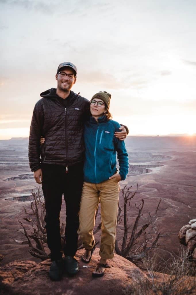 Two people standing on an overlook at sunset.