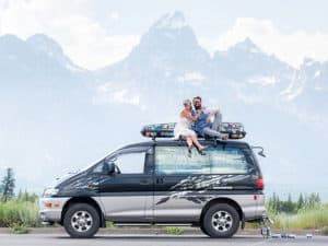 Be Old Later couple embracing on top of their rig in the mountains