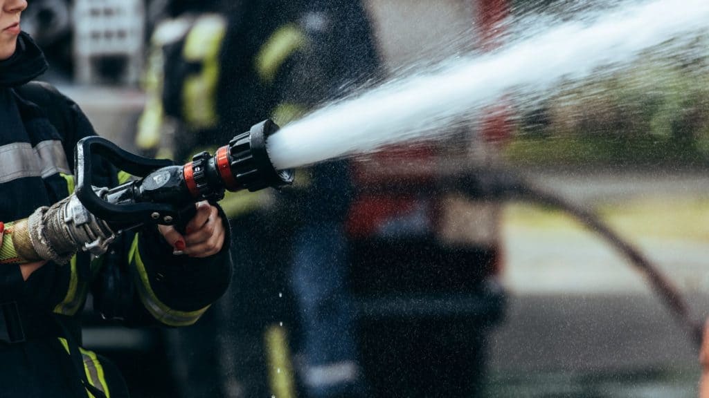 a firefighter holding a firehose that is shooting out water