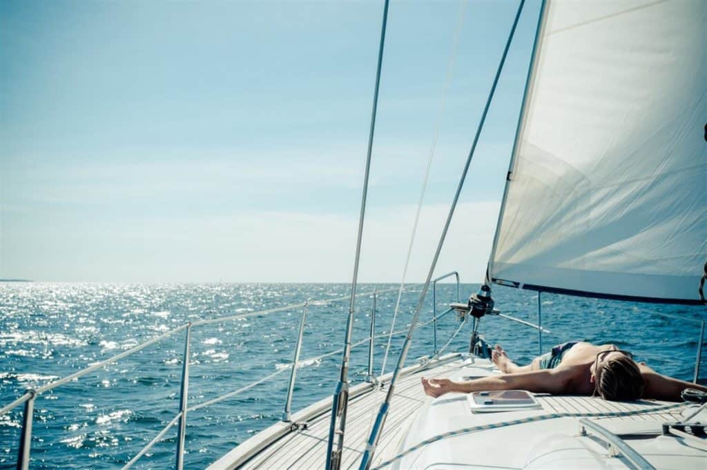 man sunbathing on the front of a sailboat