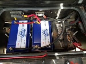 Two Battle Born Batteries next to a lead-acid starter battery, which are stored under the stairwell of Sabrina and Kenny's RV.