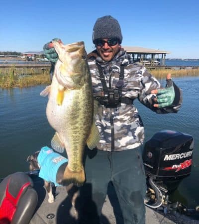 Mikey Meisenheimer holding a large mouth bass that he caught on his bass boat