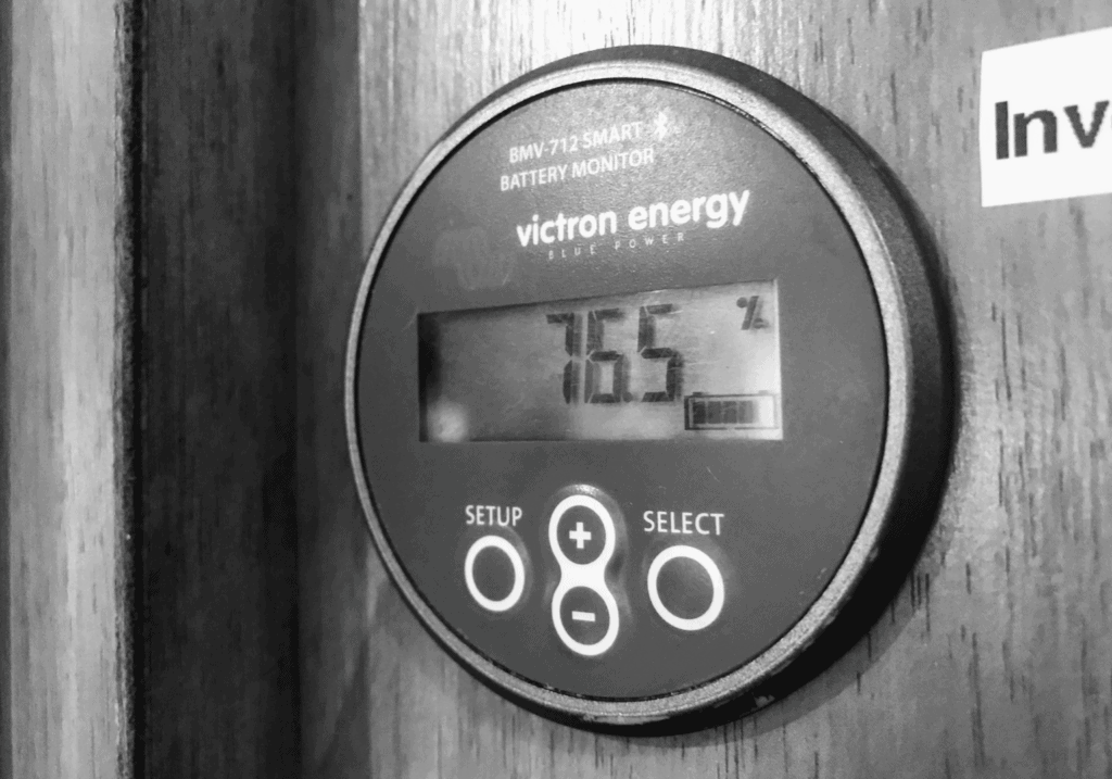 76.5% remaining charge of battery system displayed on a Victron Energy battery monitor. Photo is in black and white.