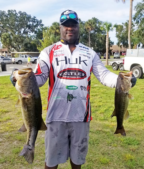 An image of Wayman holding up two fish. 
