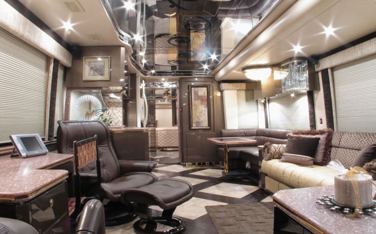 Interior shot of a Prevost motorhome with lights on and white/brown interior. 
