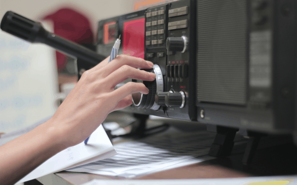 Hand adjusting a knob on a ham radio