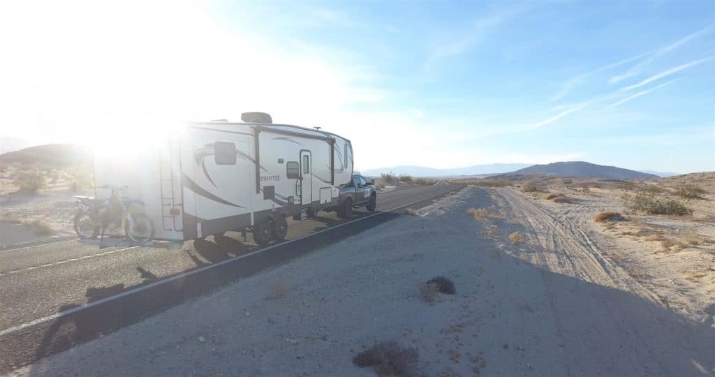 Fifth wheel RV being towed in the middle of the desert