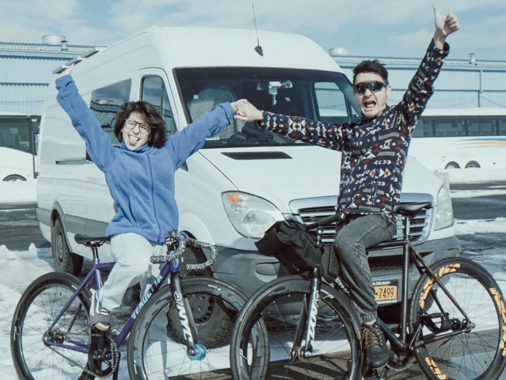 Francisco and Lulu of BFixie posing on bikes in front of their white Sprinter van