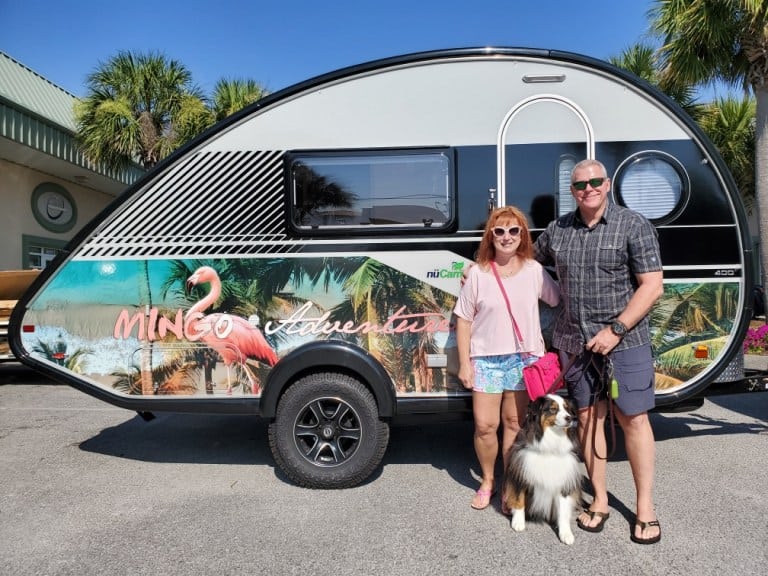 A couple standing with their dog in front of their NuCamper