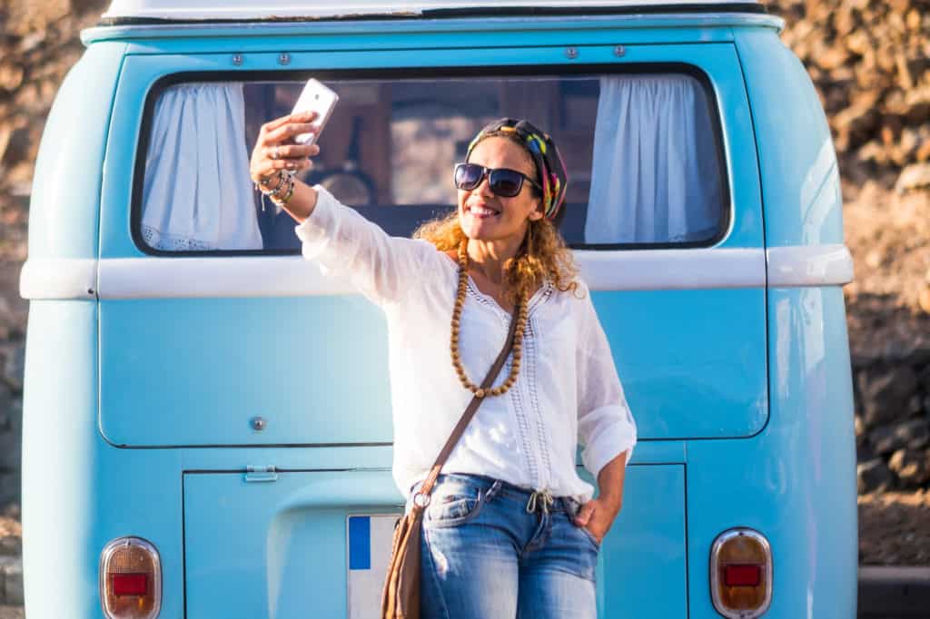 woman using cell phone to take a selfie while camping