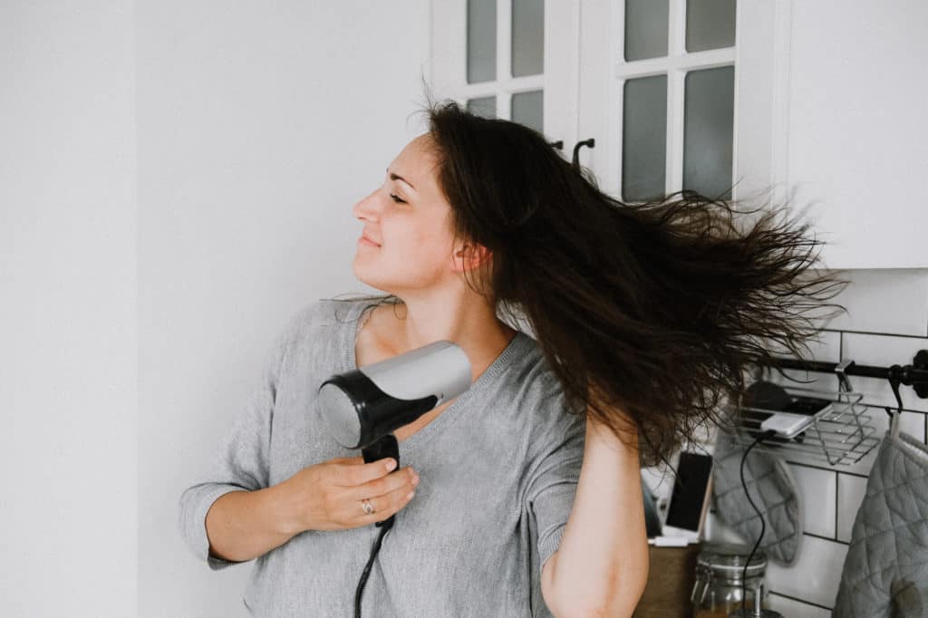 woman blow drying her hair with a blow dryer