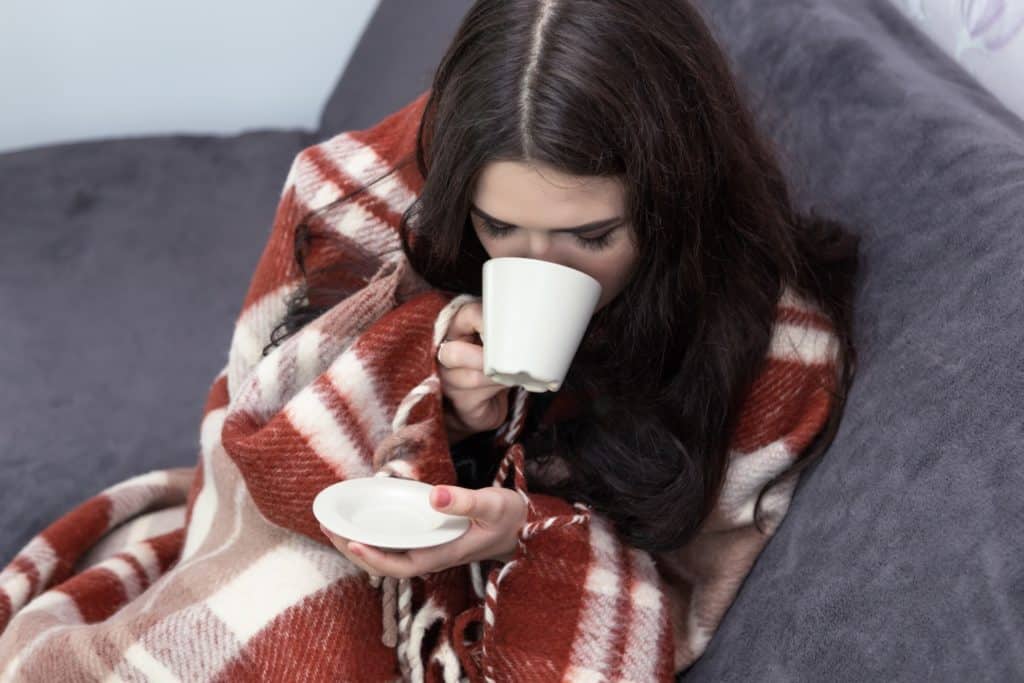 woman in blanket drinking hot beverage