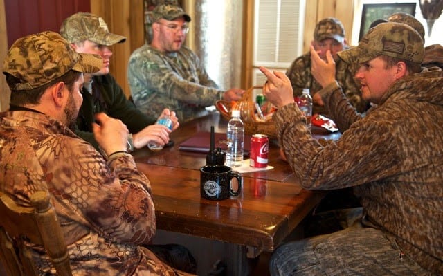 Veterans gathered around a table talking and wearing camo
