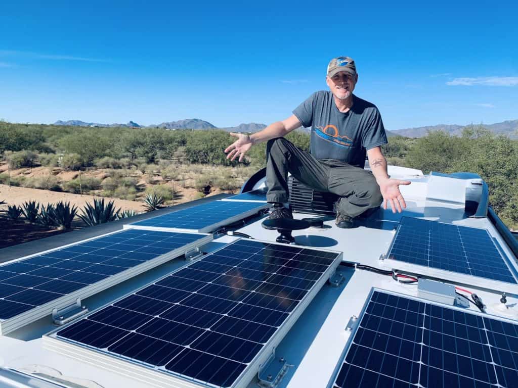 always on liberty rv solar panel installation. Man standing on top of RV around his solar panels