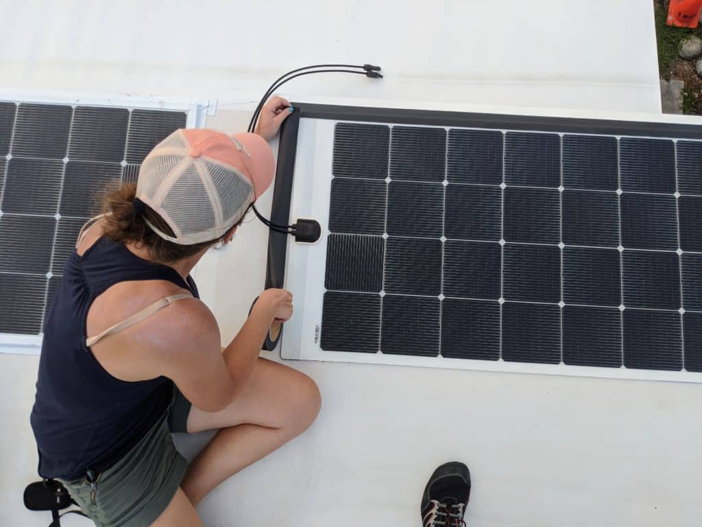 woman installing solar panel on rv roof