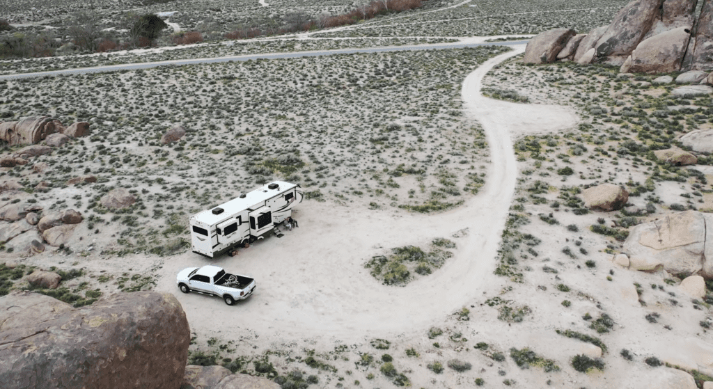 drone shot of a white truck and RV boondocking in the desert