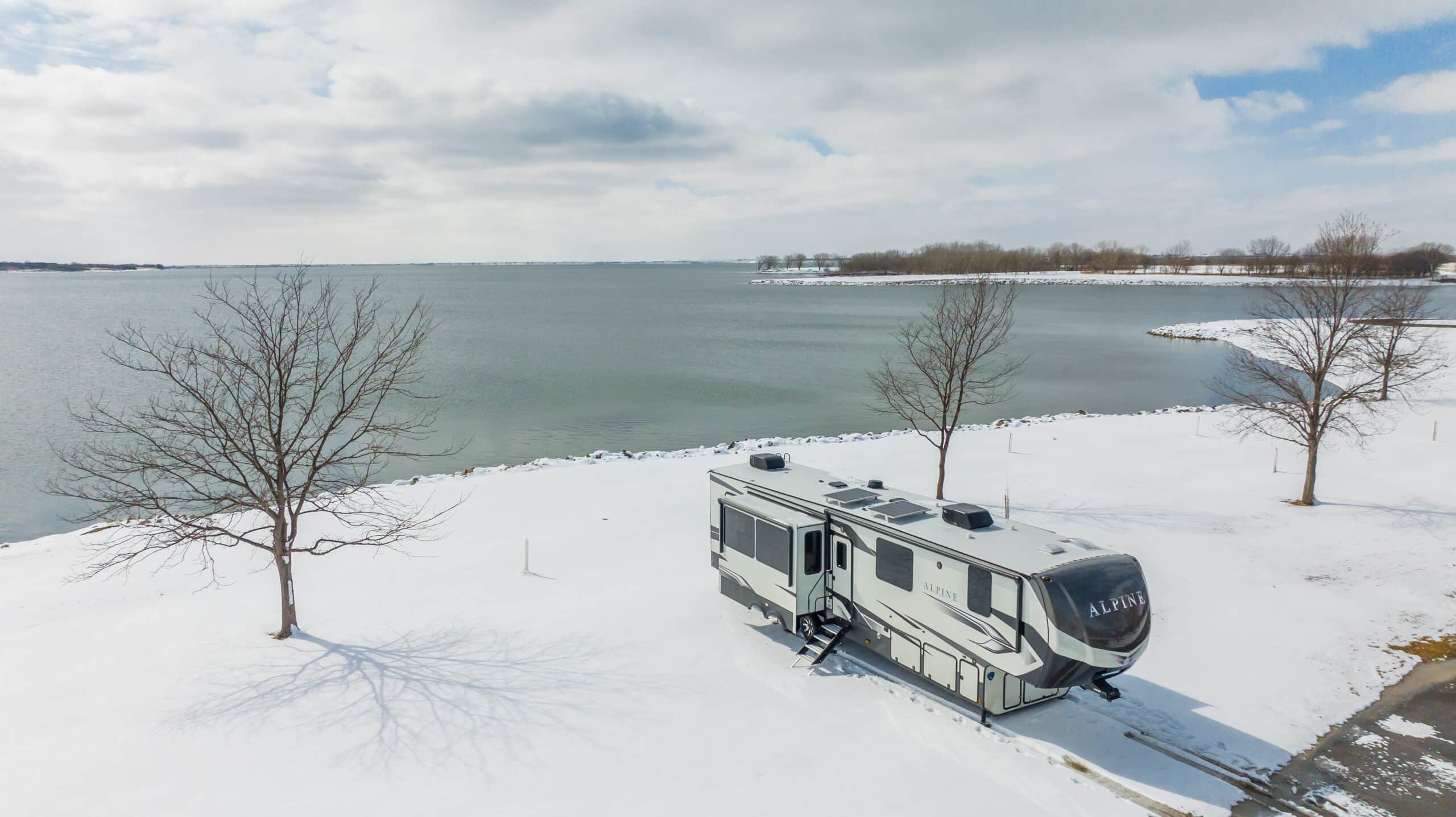RV in the snow by a lake with a solar panel on the roof