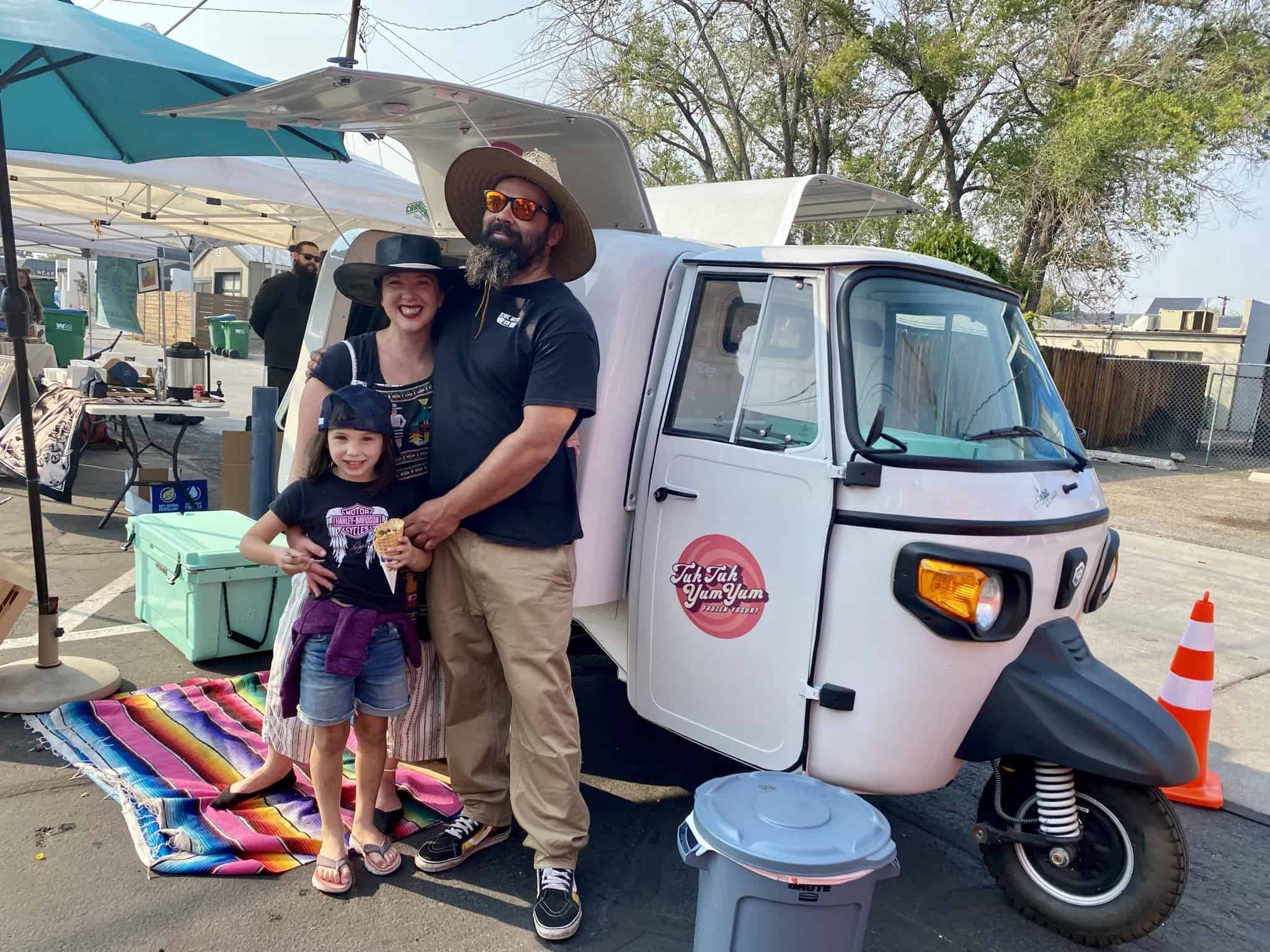 The owners of Tuk Tuk Yum Yum, frozen yogurt truck, standing in front of their rig