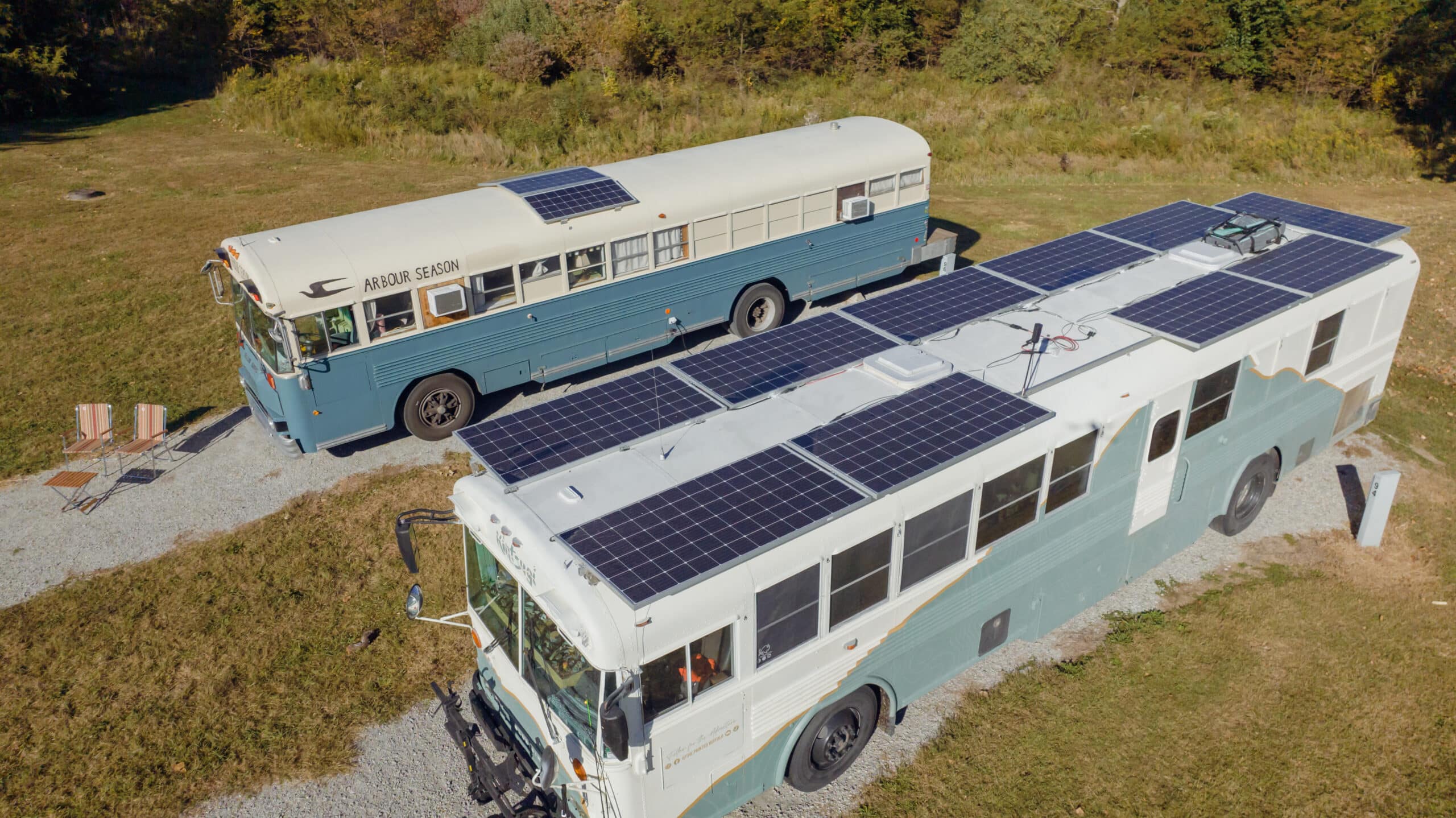 Two Converted Skoolies Parked Next to Each Other with Solar Panels on Top