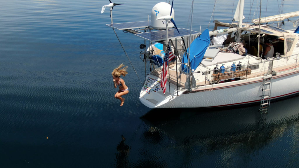 Woman jumping off of a sailboat into water