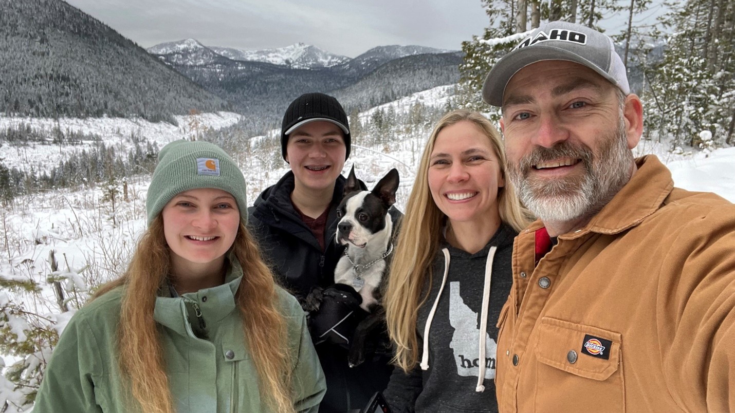 The Johnson family (dog included) posing for a selfie in snowy mountains