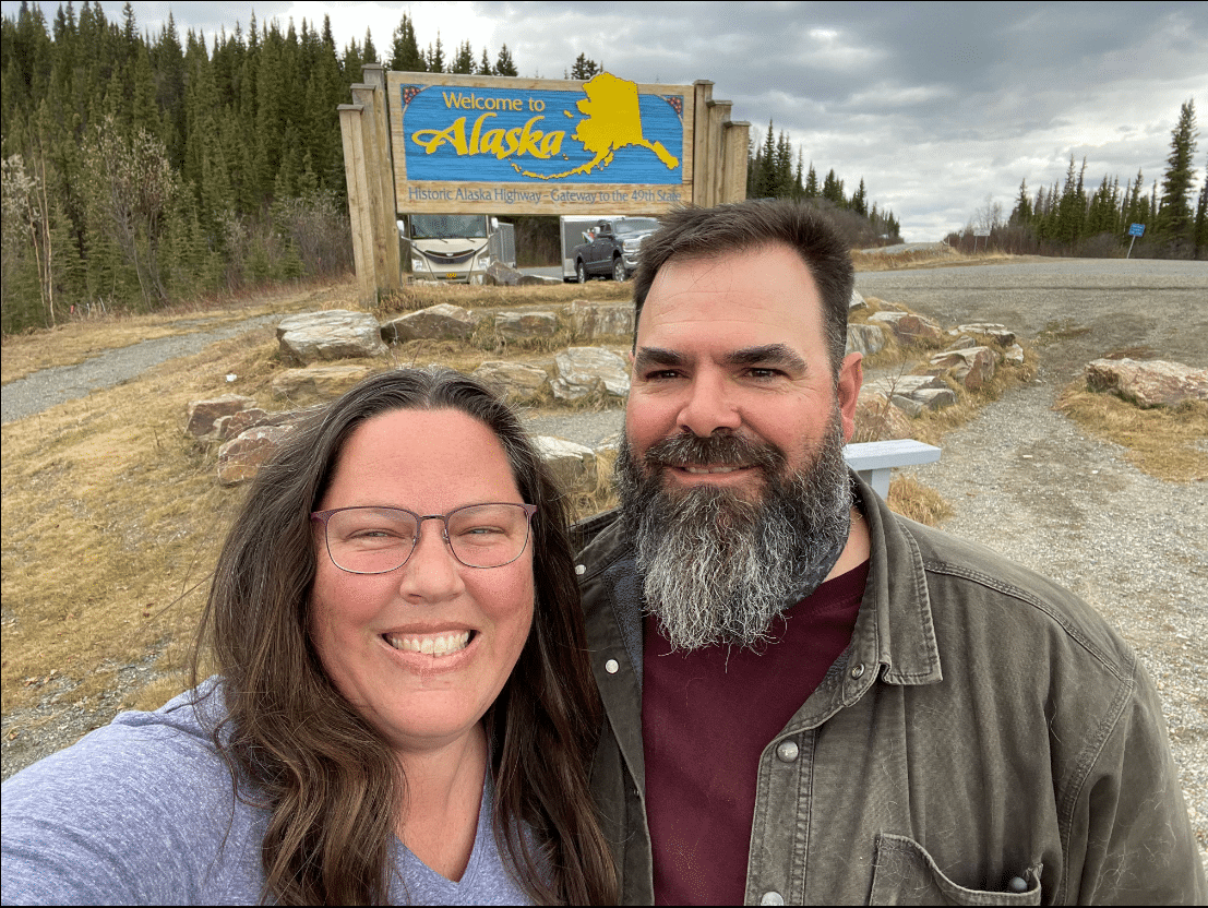 RVing to Alaska Stacy and Gar in Front of Welcome to Alaska Sign