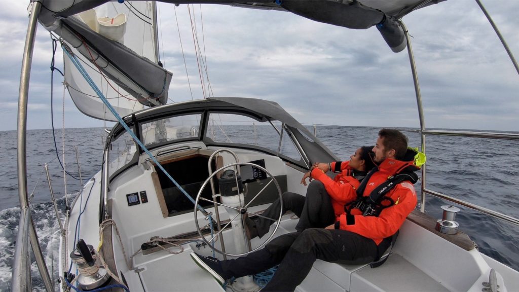 Dan and Kika of Sailing Uma bundled up and underway on their sailboat.