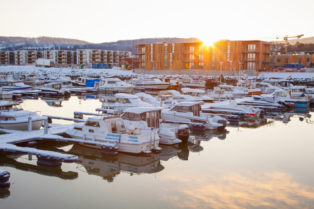 snowy marina in winter with sunrise over buildings