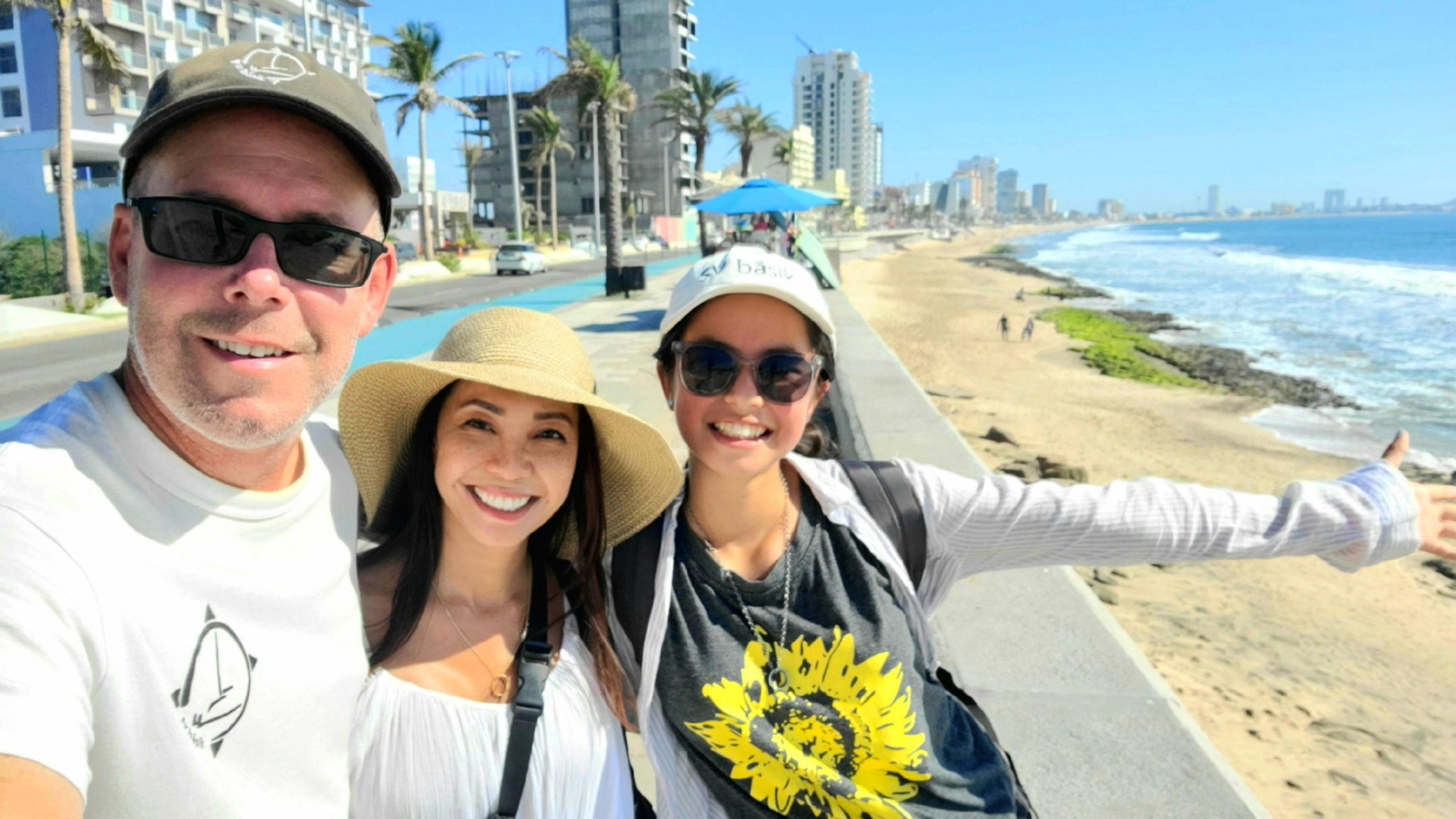 Crew of S/V basik smiling for a selfie on the shore of a beach