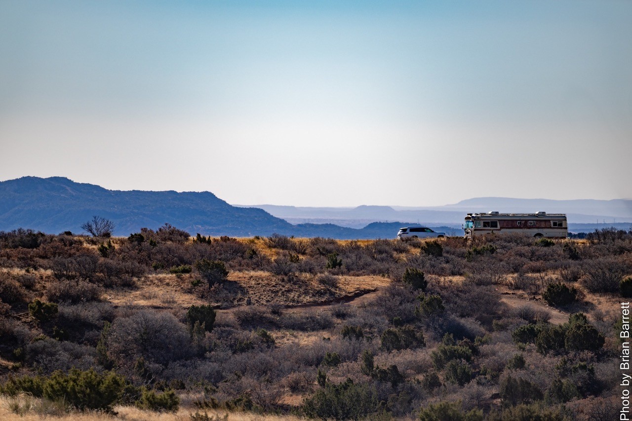 Car and Skoolie in the Distance in a Desert Landscape