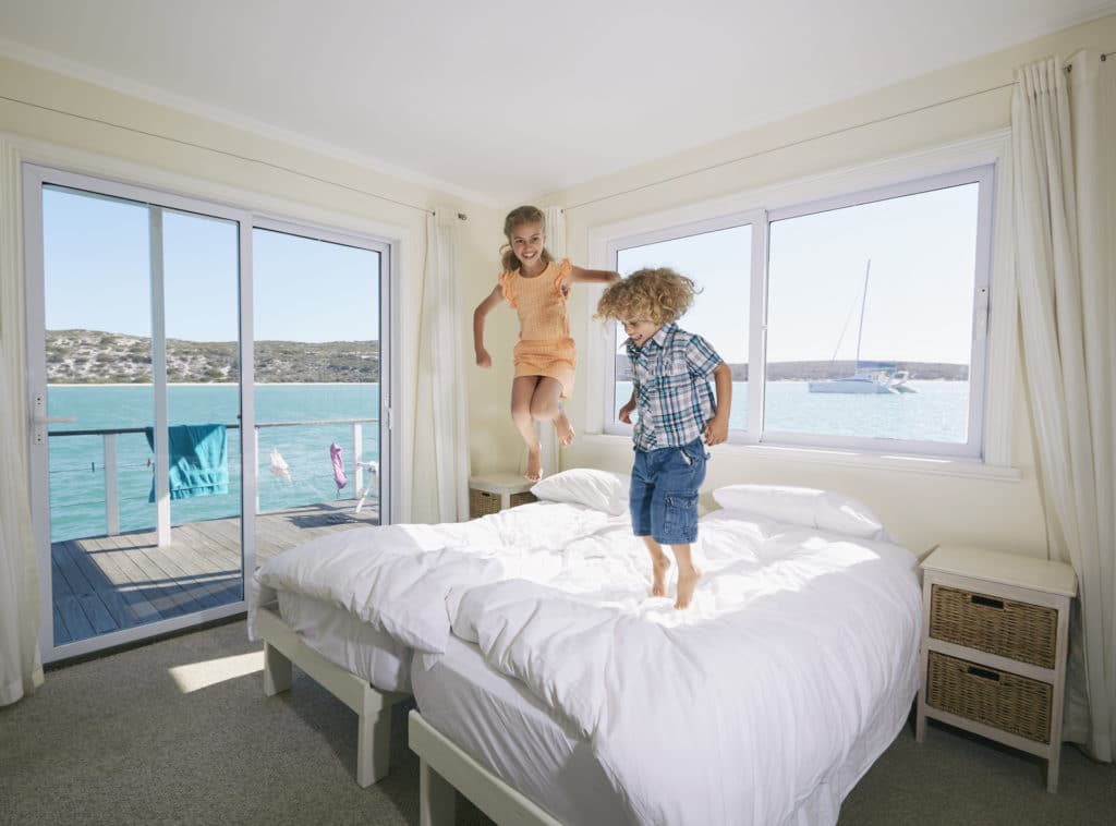 Boy and girl jumping on bed in houseboat