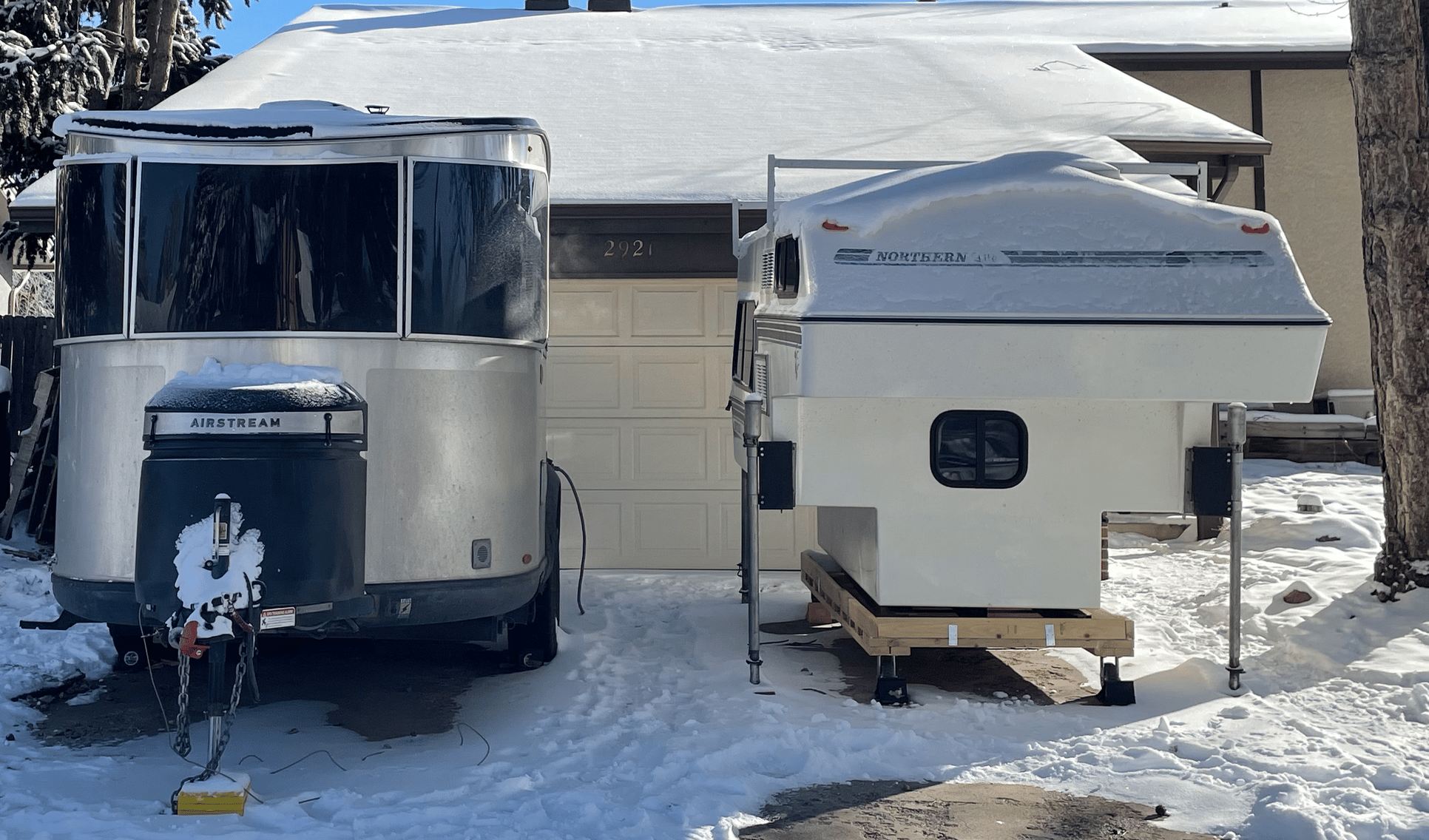 Airstream Basecamp Next to a Northern Truck Camper in a Driveway