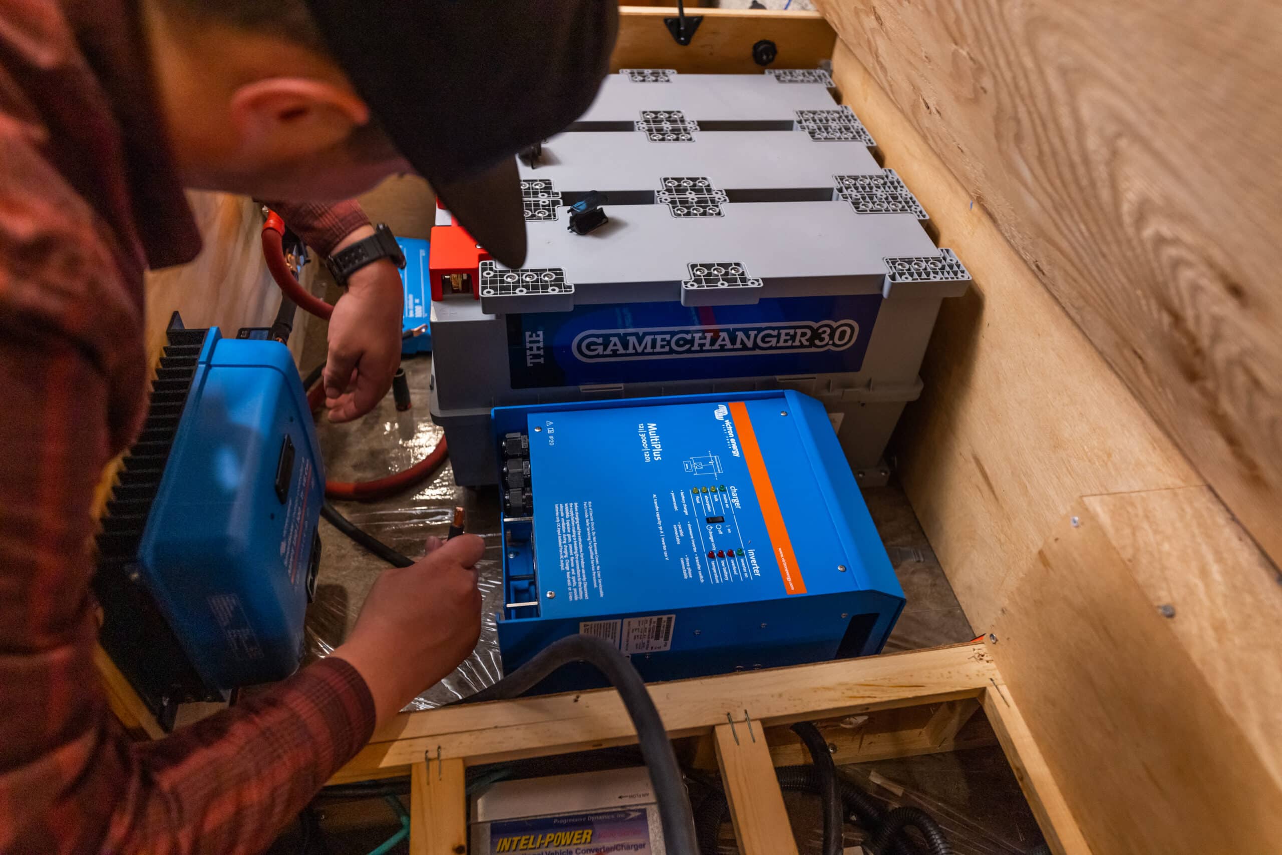 Man installing Battle Born Batteries and Victron Energy components into a cabinet