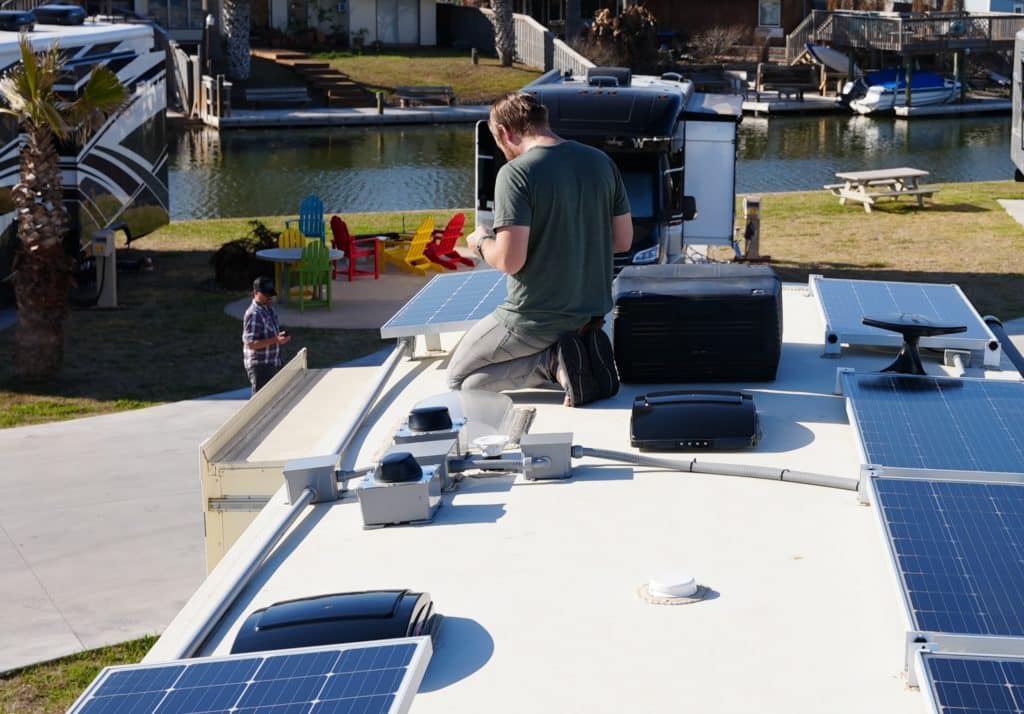 man working on roof of rv on solar panels