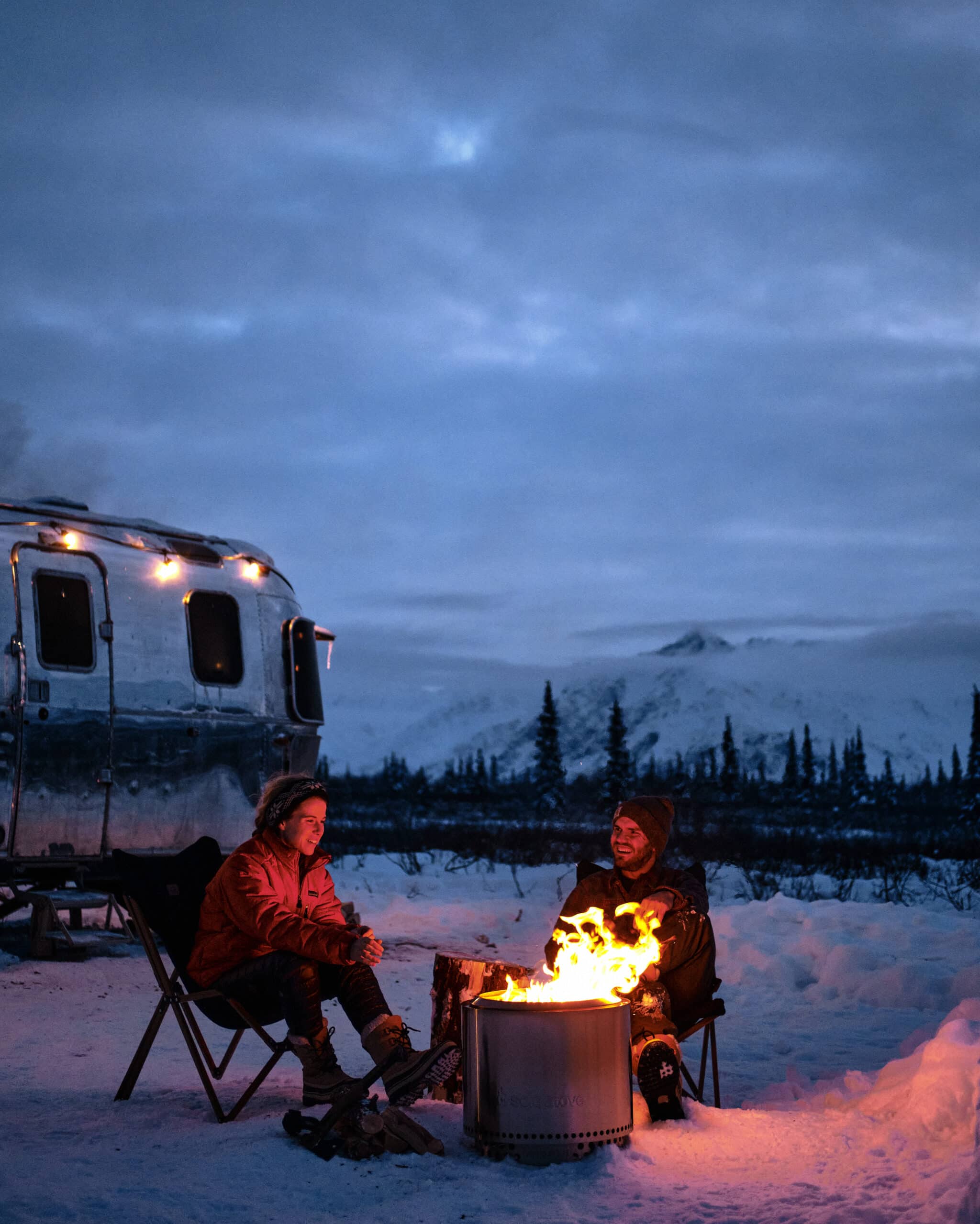 Two People Enjoying a Campfire in the Snow at Night in Alaska