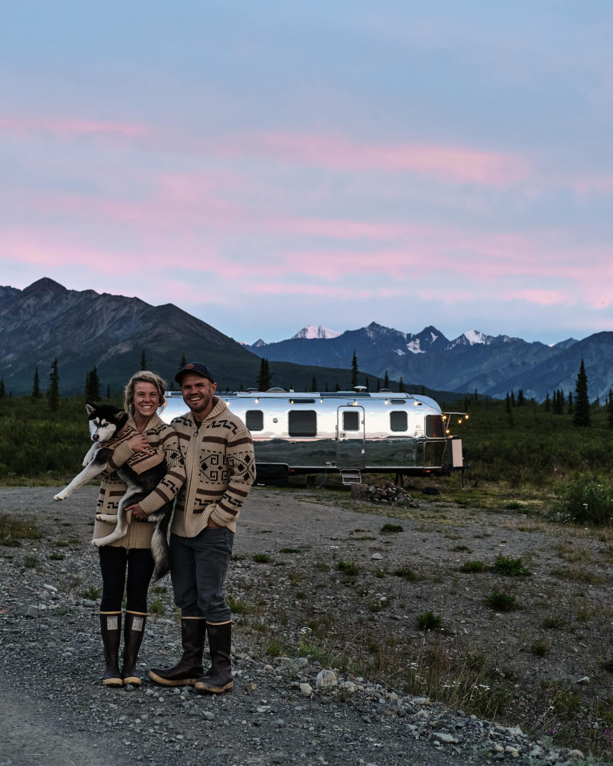 Two People and Their Puppy in Front of Their Airstream Camper in Alaska