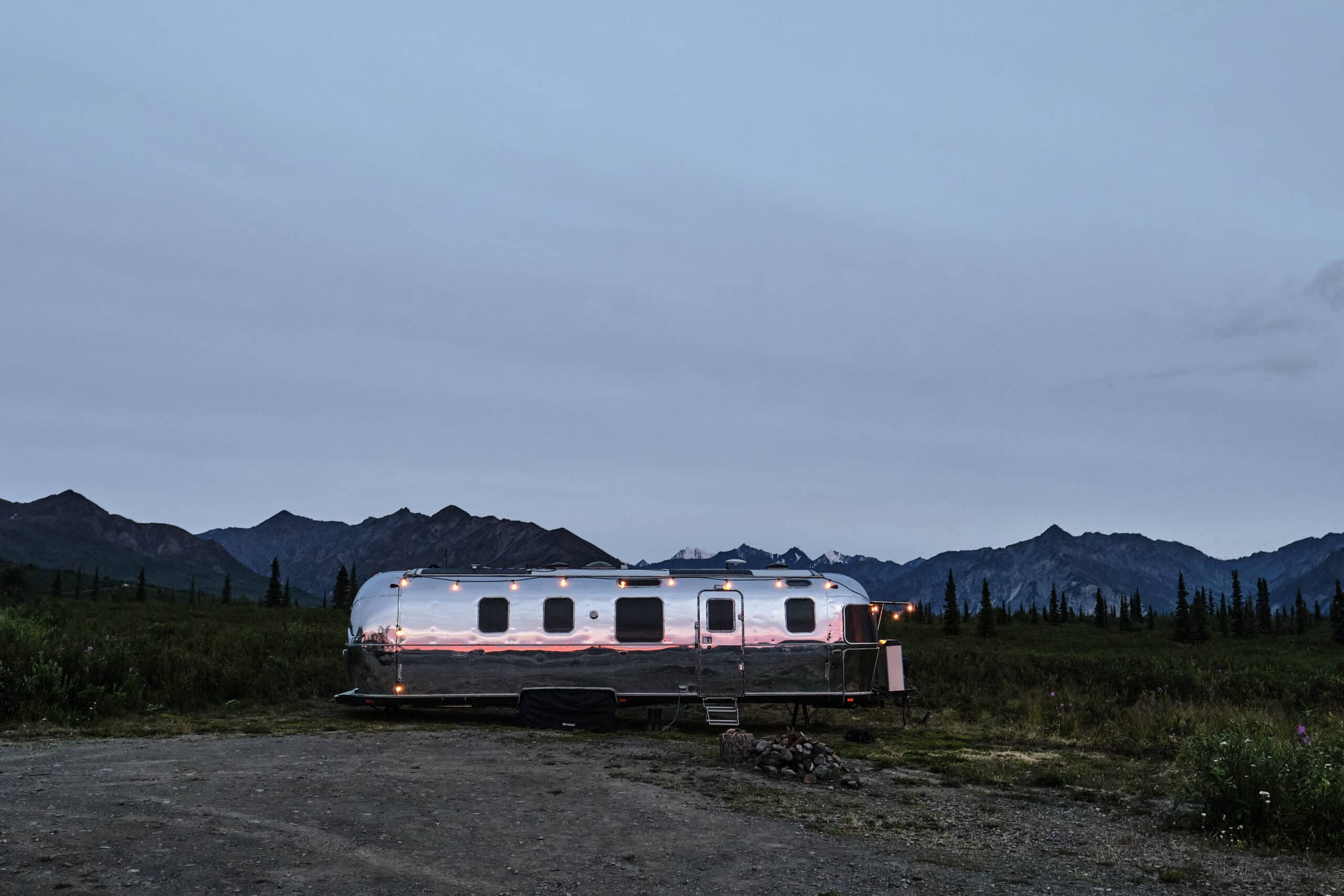 Airstream Camper Surrounded by Trees and Mountains in Alaska