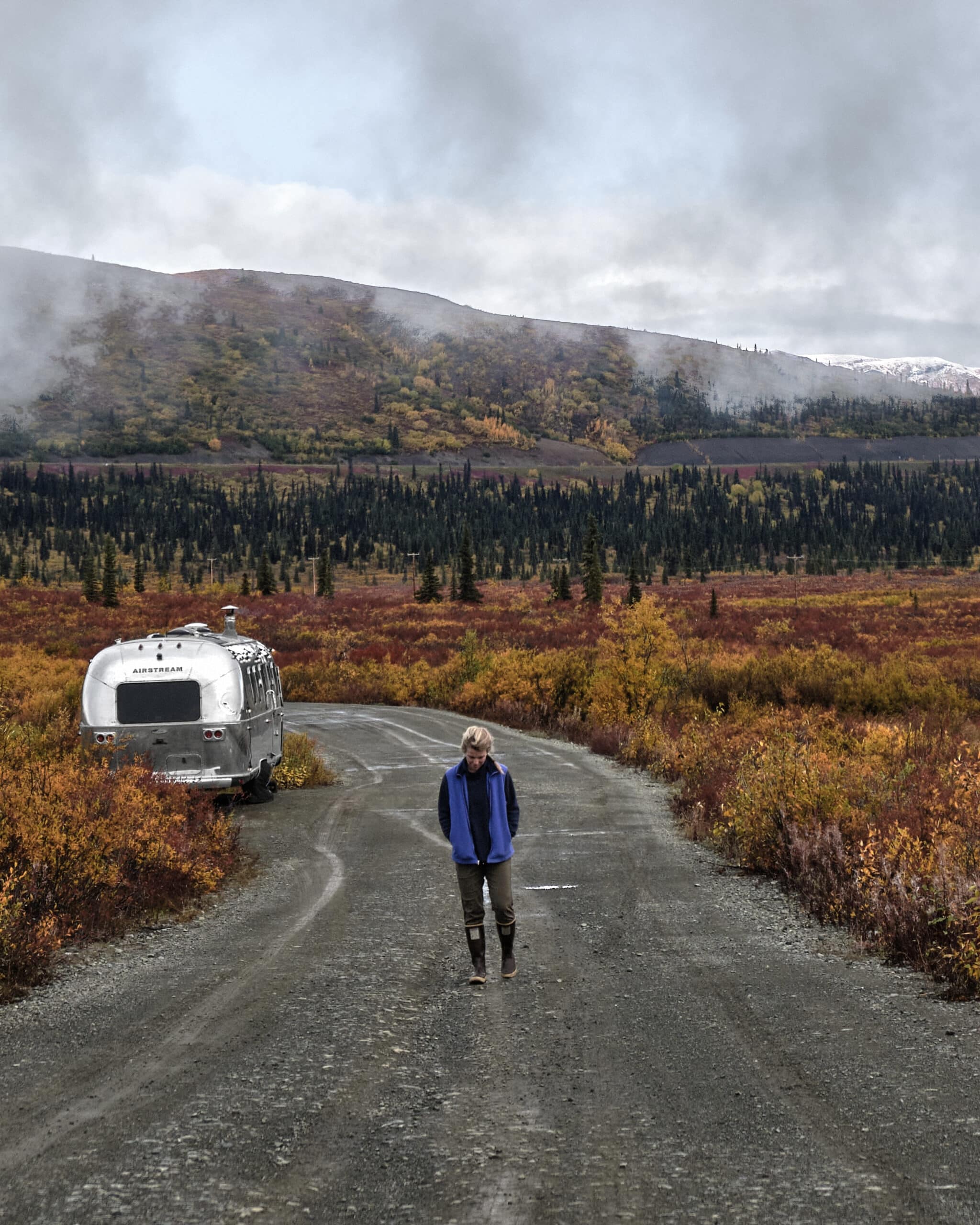 Kendall Strachan on a Road Surround by Fall Colors in Front of Her Airstream Camper in Alaska