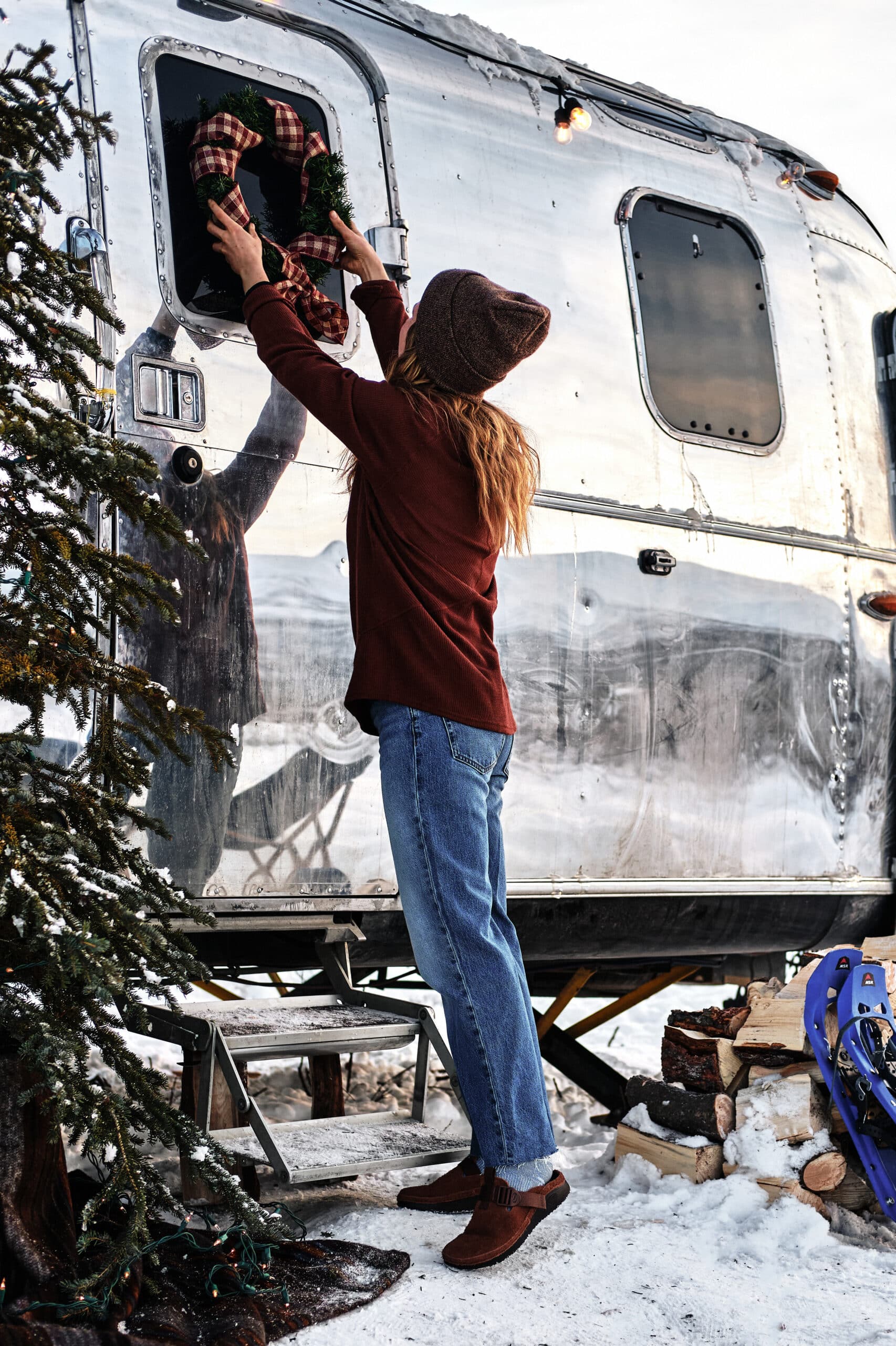 Hanging a Wreath on an Airstream with a Christmas Tree in Front
