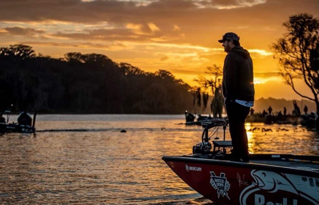 john cox standing on the front of his bass boat looking at the sunset