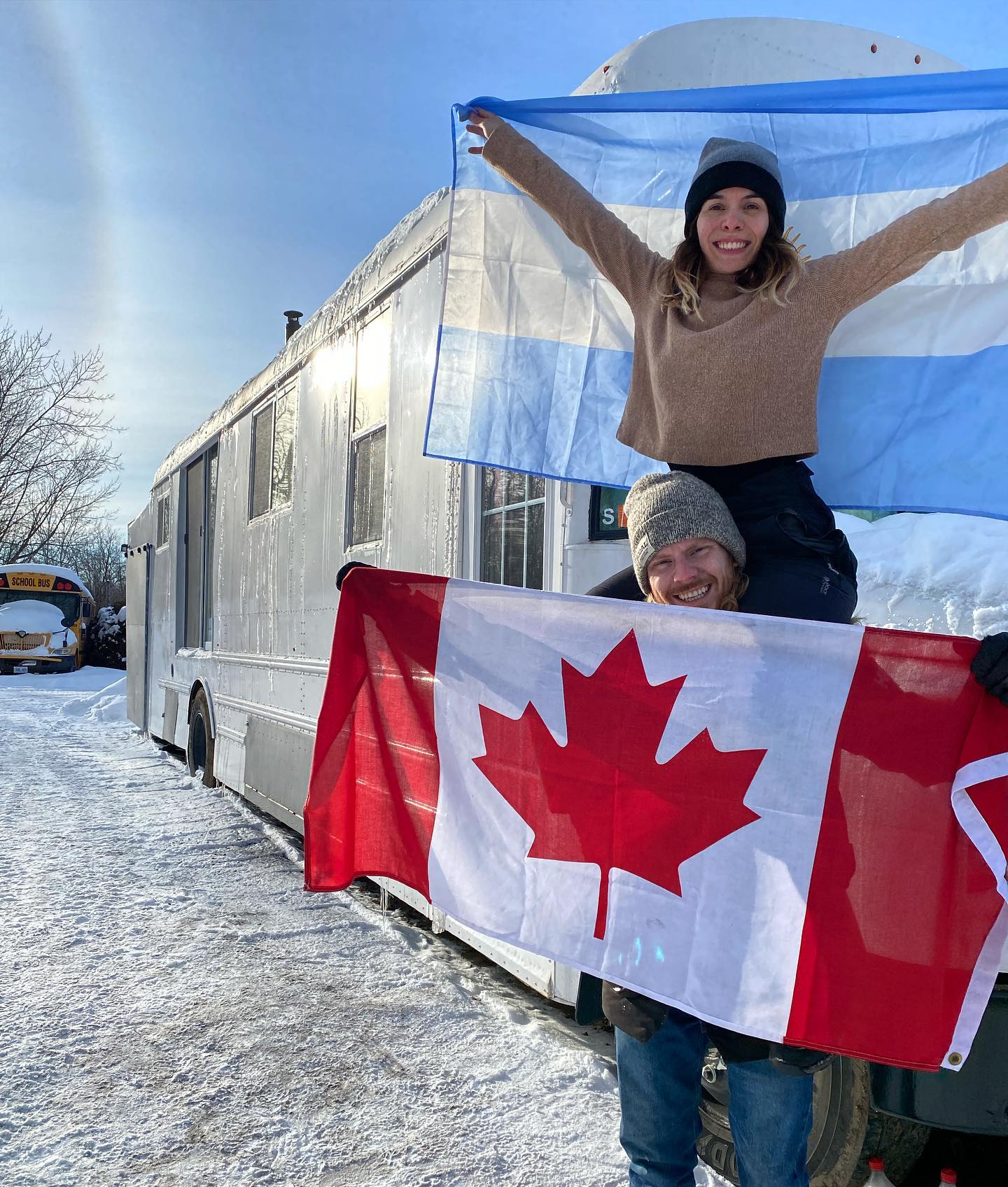 Gabi and Tyler holding a Canadian and Argentinian flag in front of their rig