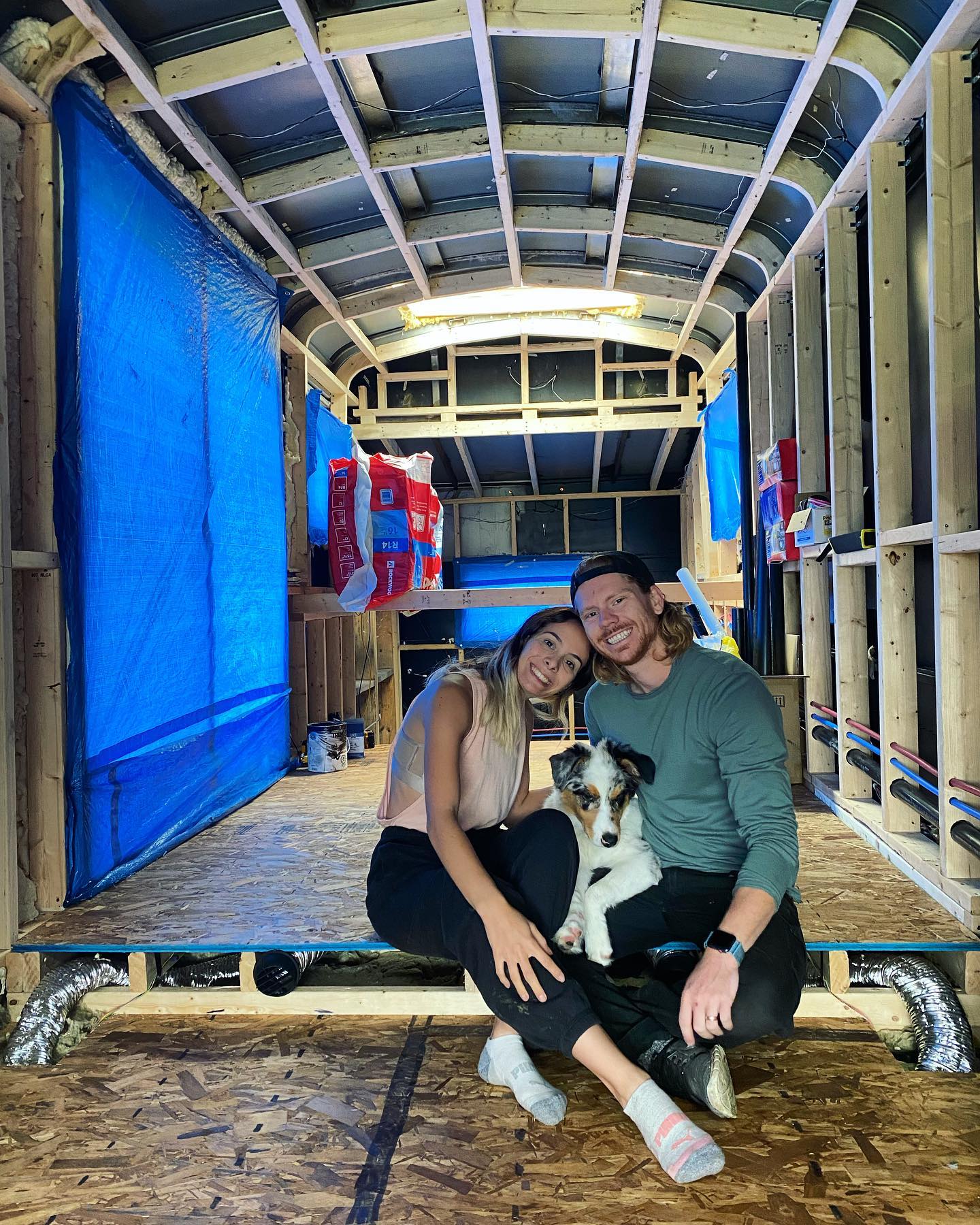 Gabi, Tyler and their dog in inside of their skoolie during renovation