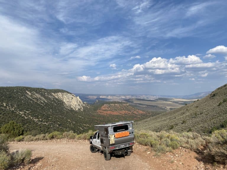 overland truck camper driving dirt road through mountains