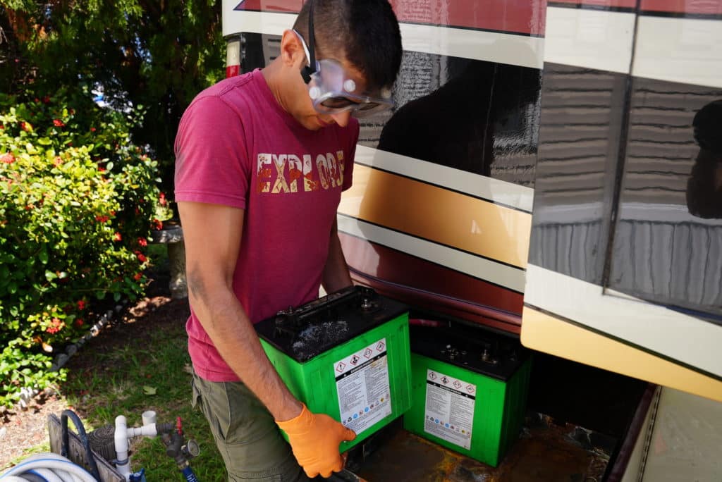 Man wearing gloves removing lead-acid batteries from his RV